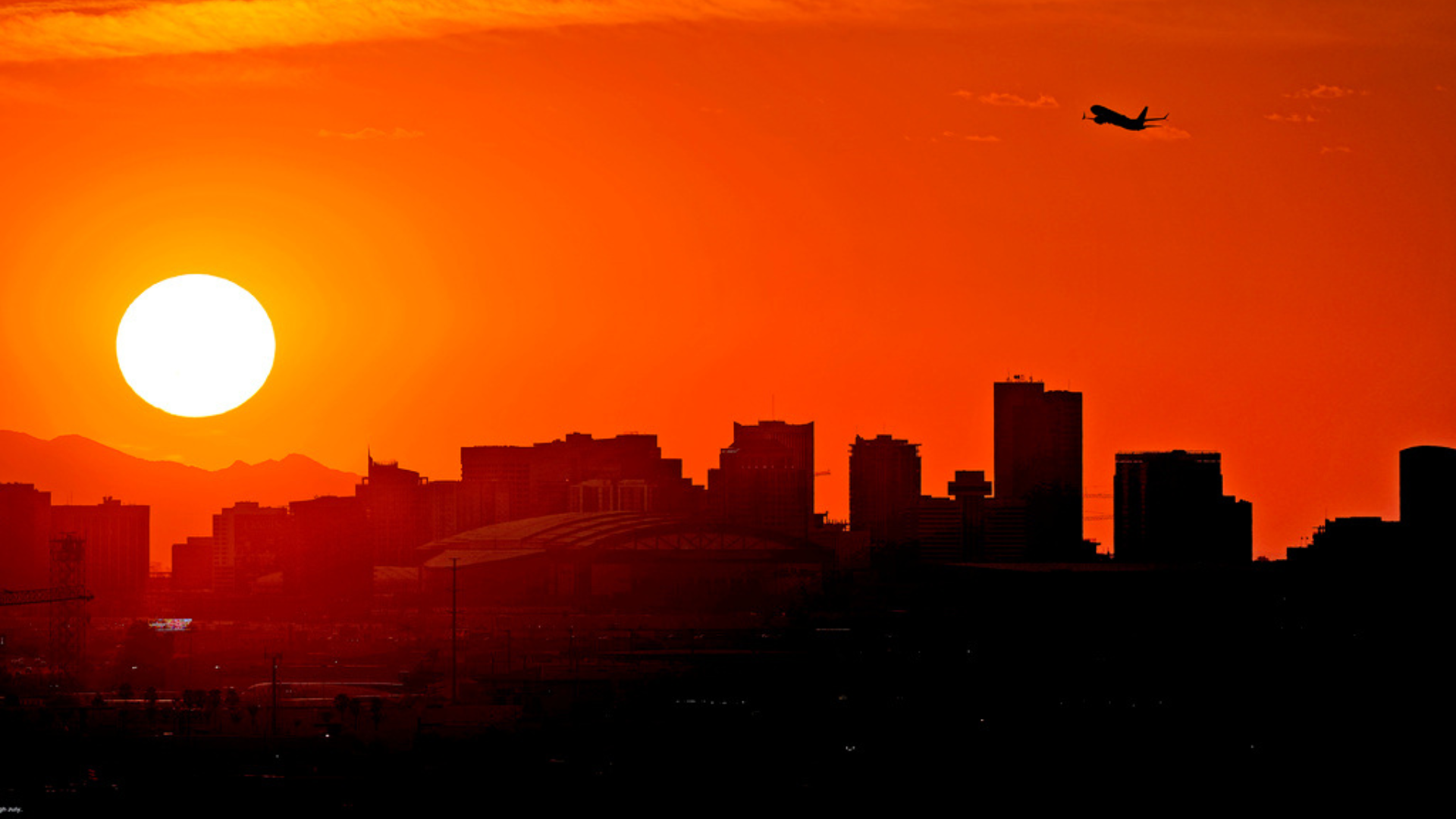 A jet takes flight from Sky Harbor International Airport as the sun sets over Phoenix