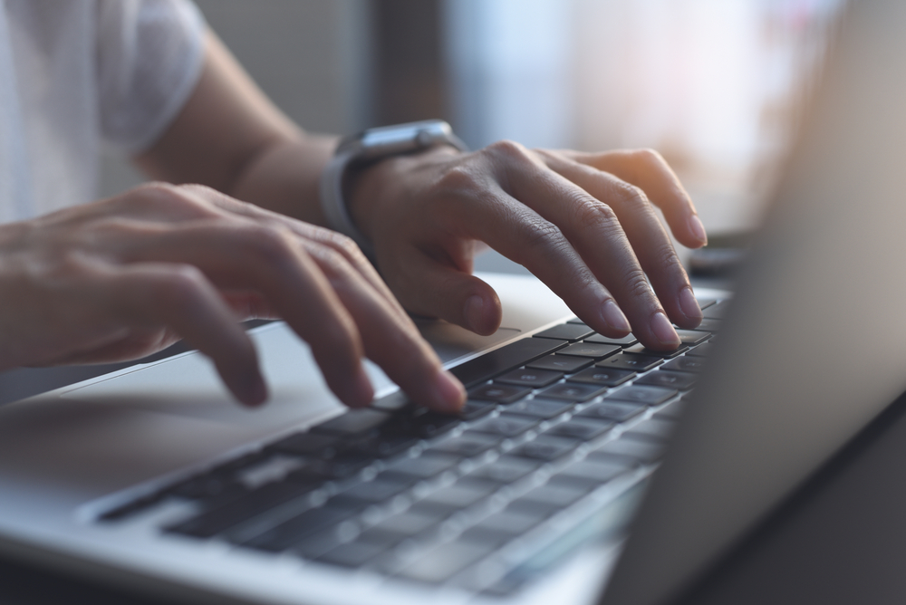Hands typing on a laptop computer