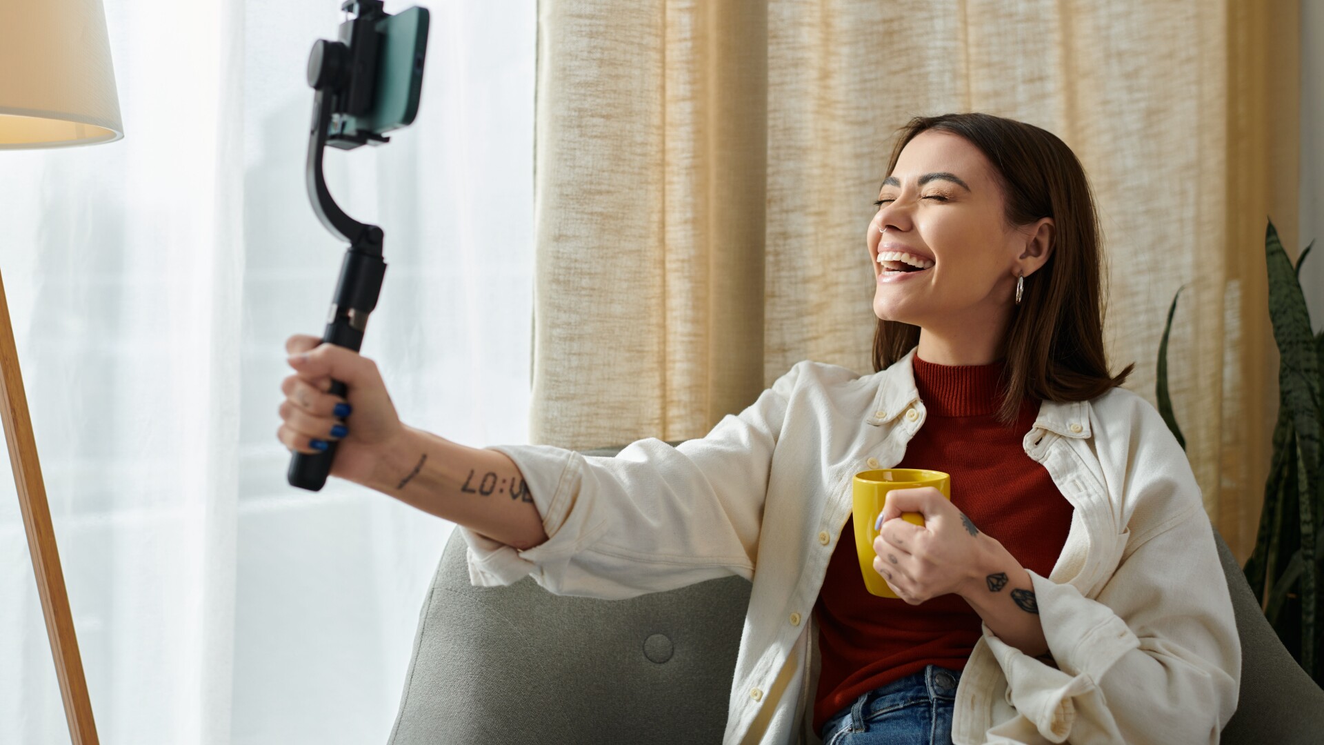 An influencer with tattoos and a cup of coffee creating a video.